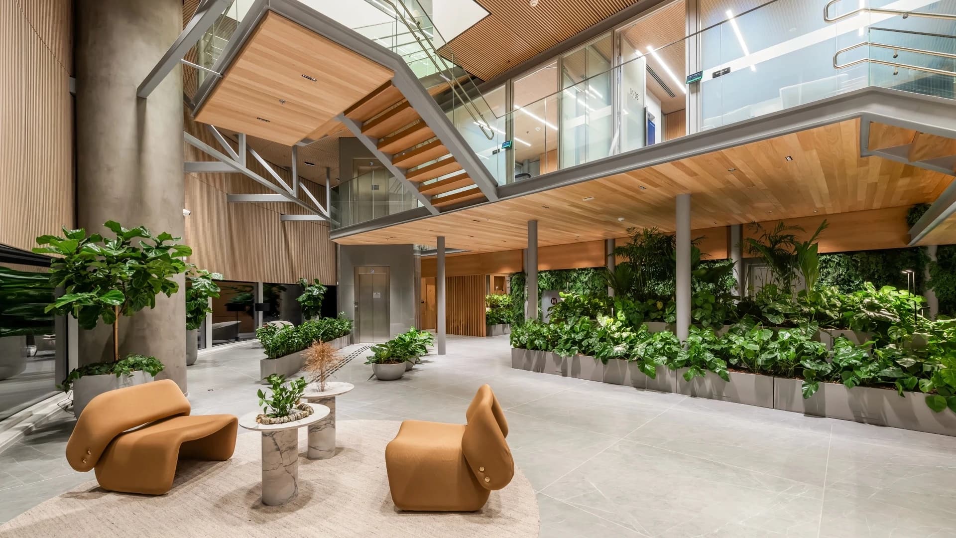 Escritório corporativo com pé-direito alto, madeira, plantas e poltronas